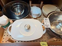 Lot overview showing Dutch oven, mixing bowls, colander, ceramic dishes