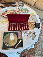 All items laid out: cheese board, spreaders, coasters, napkin rings, silver-plate utensils, trivet