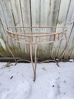 Full view of metal demilune table frame standing on snow