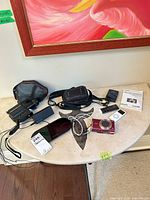 Overview of all electronics on tabletop: Fujica camera, Canon camera, two iPod Nanos, Mophie charger, manual, case, cables