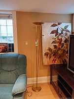 Full view of metal torchiere floor lamp beside furniture