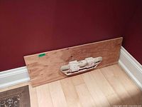 Full view of plywood panel with attached hangboard leaning against wall