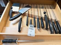 Drawer view showing two cleavers, multiple knife handles in grooves, honing steel