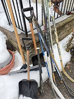 Group showing shovels and clustered hockey sticks leaning on railing