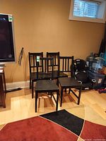 Four black-brown wooden slat-back chairs grouped