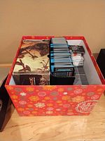 Overview of holiday box containing Magic: The Gathering box, stacks of sleeved cards and loose cards