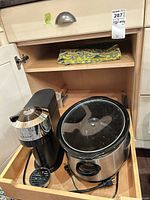 Drawer showing Nespresso coffee maker, Crock-Pot slow cooker with lid, folded tablecloth above