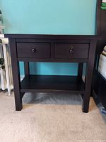 Front view of dark wood nightstand showing drawers and shelf