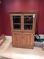 full frontal view of oak cabinet showing two glass doors above two wood doors