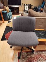 Full front view of grey upholstered armless swivel chair on caster base