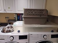 Carrier on top of tote next to dog bowl