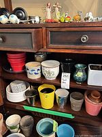 Overview of two cabinet shelves filled with assorted plant pots