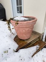 Large terra cotta planter with snow and ivy visible