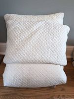 Stacked white quilted duvet cover beneath two matching pillows