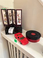 Screen, model car and round trinket box grouped on shelf