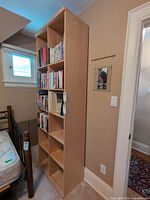 Full view of tall light wood bookcase in room