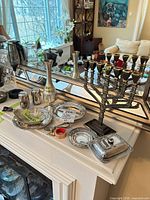 Group view of silverplate items on mantle: menorah, dishes, vase, shakers, trinket box