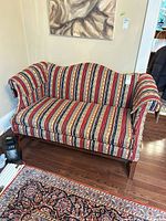 Front view of striped upholstered loveseat showing full design and wood legs