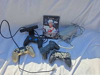Group shot of all items: three DualShock 4 controllers, PS4 Camera v2, PS2 controller, Wii U AC adapter, GameCube NHL Hitz 20-02 game