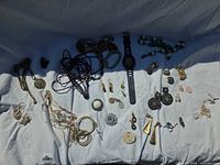 Entire lot laid out showing variety of jewelry pieces and watch