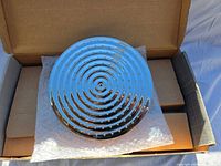 Round chrome shower head inside open box with protective bubble wrap and cardboard inserts