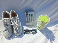 Overview of sneakers, brush set, sunglasses, candle
