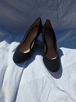 Front view of both black suede pumps showing toe shape and material