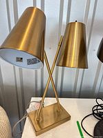 Full view of brass table lamp showing dual conical shades and crossed arms