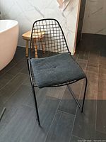 front view of black wire frame chair with knitted cushion