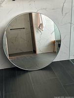 Front view of round metal-framed mirror against tiled wall