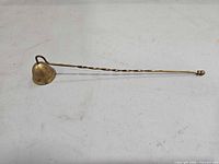 Full view of brass candle snuffer showing length and design