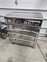 Front and side view of mirrored silver dresser showing four drawers