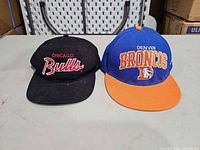 Front view of both hats showing team logos and brim colors