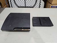 PS3 Slim and PS2 Slim consoles side by side top view