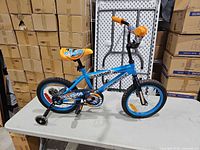 Full left-side view of blue/orange Supercycle Illusion 16" bike on table