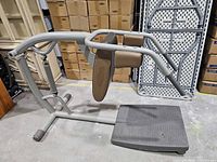Side view of entire TechnoGym Roman chair showing steel frame, pads, foot platform and wheels