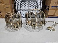 Both brass and glass pendant chandeliers side by side on table