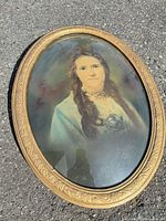Full view of oval portrait with gold frame lying on pavement