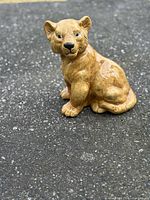 Front three-quarter view of ceramic lion cub figurine showing face, body and glaze condition