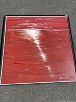 Full view of square red seascape painting in floating frame on pavement