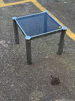 Angled view of side table showing chrome legs, smoked glass top