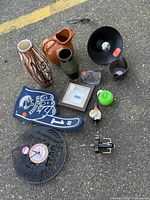 All items arranged on pavement showing variety of ceramics, clock, lamp, foam finger, framed art, etc.