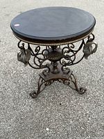 Full view of vintage iron table showing round top and ornate base