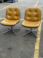 Front view of both caramel swivel chairs on chrome bases
