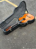 Guitar inside open hard case on ground