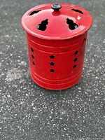 Full view of red steel fire bucket with lid on, showing star perforations