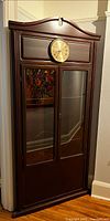 Full view of closed pine corner display cabinet showing clock and glass doors