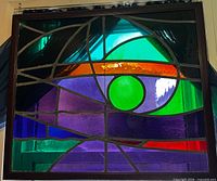 Full view of framed stained glass panel showing abstract design and frame