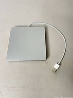 Top view of Apple USB SuperDrive showing silver aluminum surface and attached USB-A cable