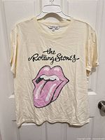 Front view of ivory Rolling Stones graphic T-shirt hanging on hanger
